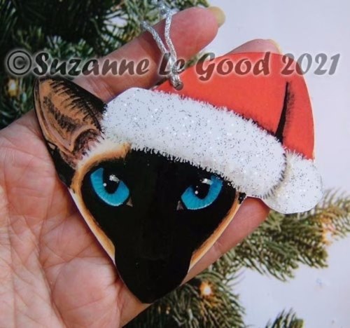 Head of a Siamese cat wearing a Santa hat; Christmas tree ornament designed by artist Suzanne Le Good.