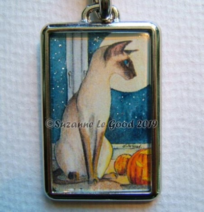 Siamese cat Halloween key ring. Siamese cat with pumpkins at his feet gazes out of the window onto a moonlit, starry night.